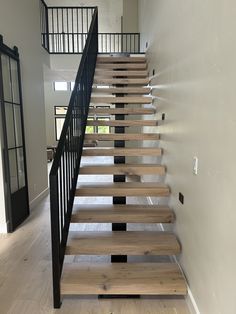 the stairs are made of wood and have black railings on each side, along with white walls