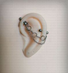 a pair of ear piercings with chains attached to them