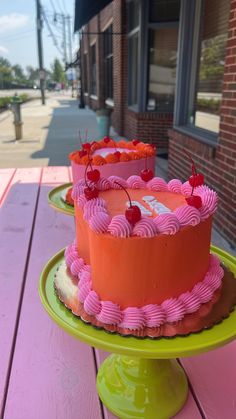 two cakes sitting on top of a green and yellow cake stand next to each other