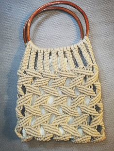 a white purse with wooden handles on a gray surface and grey fabric behind the bag