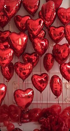 many red heart shaped balloons hanging from strings