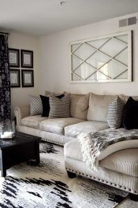 a living room filled with lots of furniture next to a wall mounted mirror on the wall