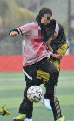 two men playing soccer in the rain