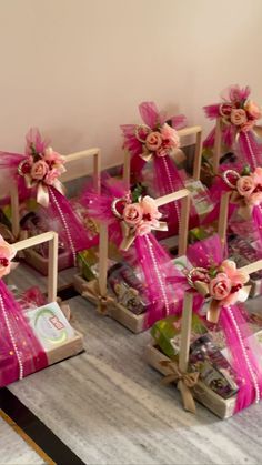 several small wooden boxes with pink ribbons and flowers on them sitting on a marble table