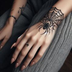 a woman's hand with a spider web tattoo on it