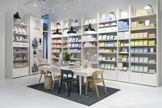 a room filled with lots of white shelves and chairs next to a table in front of a bookshelf