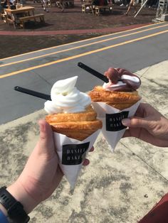 two ice cream cones with toppings in their hands