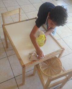 a young boy sanding on top of a wooden table