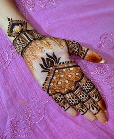 a woman's hand painted with hennap on top of a purple blanket