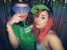 two young women with red hair and green hats are posing for the camera while wearing blue sunglasses