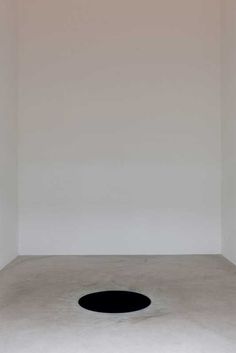 an empty room with a black hole in the floor and no one standing inside it