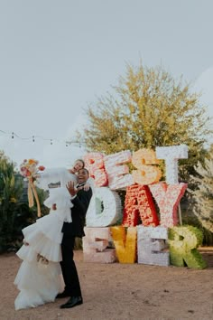 a bride and groom standing in front of large letters