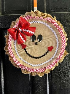 a straw hat with a face and red bow hanging on the front door to give as decoration