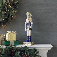 a nutcracker figurine sitting on top of a mantle next to presents