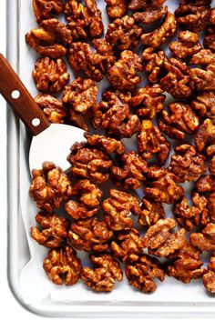 a tray filled with nuts next to a wooden spoon