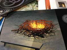 a fire pit made out of sticks and twigs on display at an art fair or exhibition