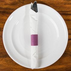 a white plate topped with a purple napkin and two black forks sitting on top of it