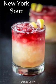 two glasses filled with drinks sitting on top of a black table next to each other