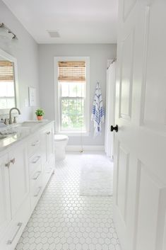 a white bathroom with hexagonal tile flooring