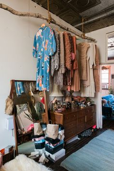 a room filled with lots of clothes hanging on the wall next to a dresser and mirror