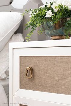 a close up of a drawer with flowers on it and a bed in the background