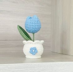 a crocheted blue flower in a white vase