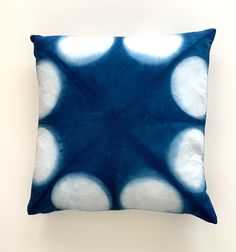 a blue and white pillow with circles on the front, sitting against a wall background