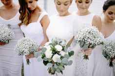 a group of women standing next to each other holding bouquets filled with white flowers