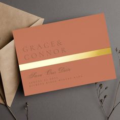 an orange and gold wedding card on top of two envelopes next to each other