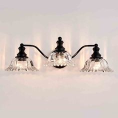 three light bathroom fixture with glass shades and black metal fittings on the wall,