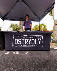 a man standing behind a table with food on it in front of a black tent