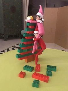 an elf is climbing up the side of a christmas tree made out of legos