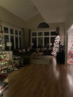 a living room filled with lots of christmas trees and presents on top of wooden floors