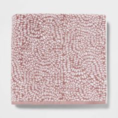 a pink and white towel on top of a white surface with an abstract design in the middle