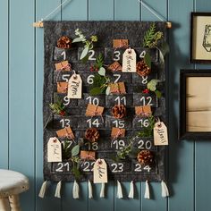 a calendar hanging on the wall with pine cones and greenery attached to it's sides