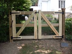 the gate is made out of wood and has two gates on each side with black hardware