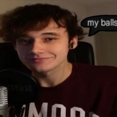 a young man is smiling in front of a microphone with an empty speech bubble above his head