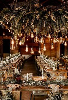 the tables are set with candles, greenery and hanging lights for an elegant wedding reception