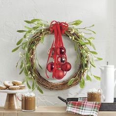 a wreath with ornaments hanging from it on the wall next to cookies and hot chocolates