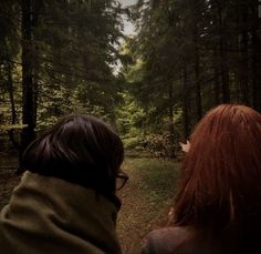 two people are looking at the woods in the distance, one is red and the other is green