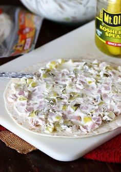 a pizza sitting on top of a white cutting board next to a jar of mustard