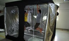 two men are jumping in the air inside a room with tarp coverings on it