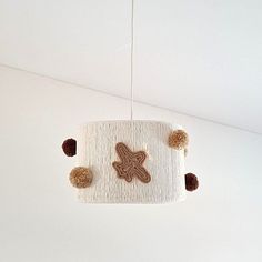 a white lamp hanging from the ceiling with brown decorations on it's lampshade