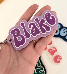 a hand holding a purple and white keychain with the word blok on it