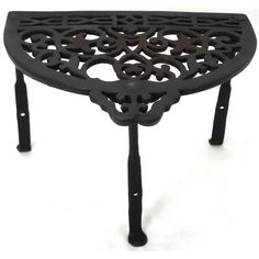 an iron table with ornate designs on the top and legs, against a white background