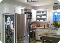 a kitchen with white cabinets and stainless steel appliances, including a refrigerator that has halloween decorations on it