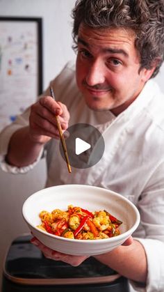 a man holding a bowl of food with chopsticks