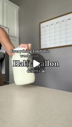 a woman pouring milk into a jug on top of a table