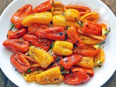 a white plate topped with lots of red and yellow peppers on top of a wooden table