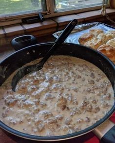 a pan filled with food sitting on top of a table next to a plate of croissants